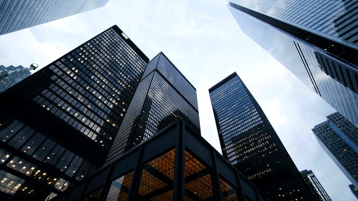 Looking up at illuminated glass bank towers against a bright sky