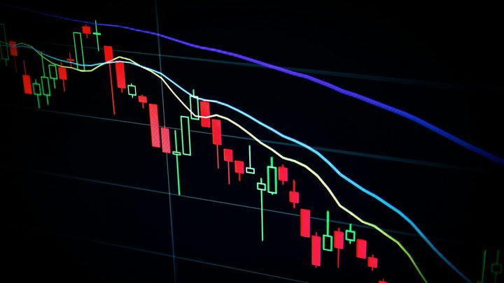 Stock market candlestick charts glowing on a trading desk monitor