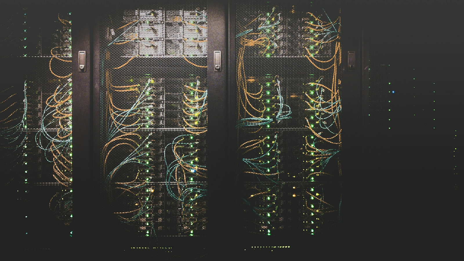 Data center server racks with glowing network cables in a dark aisle